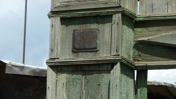 На левом столбе видна старая квадратная табличка, на которой находится полуистлевший номер дома